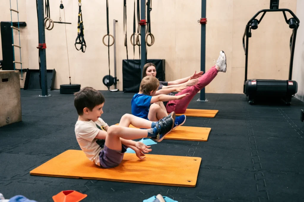 Dzieci ćwiczą na pomarańczowych matach podczas CrossFit Kids