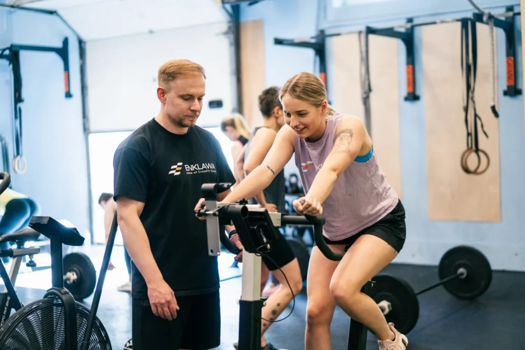 Trener wspiera klubowiczkę na rowerze powietrznym